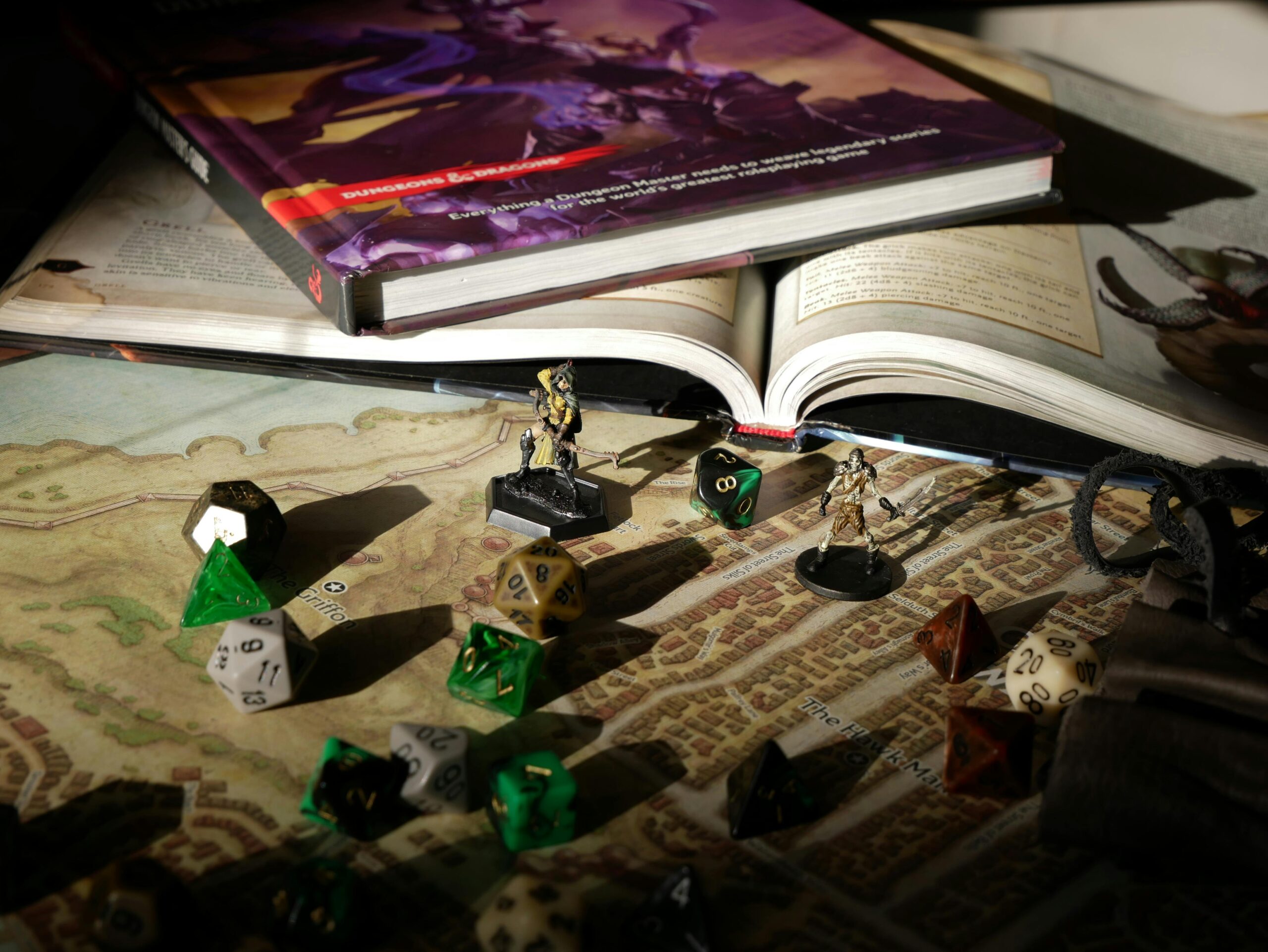 Dados de RPG, miniaturas e livro de D&D em uma mesa com mapas